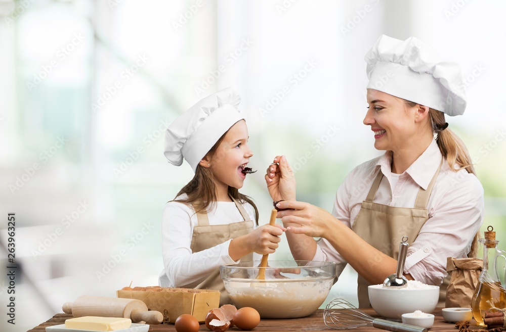 Portrait of adorable little girl and her mother baking together