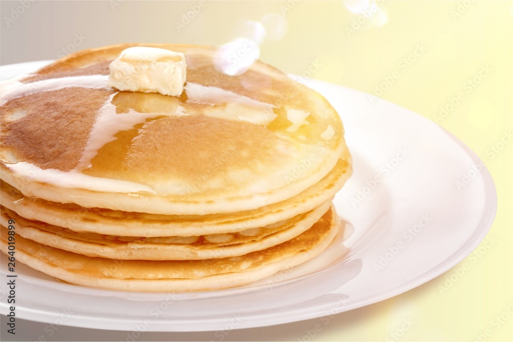 Stack of tasty pancakes with butter on a white plate