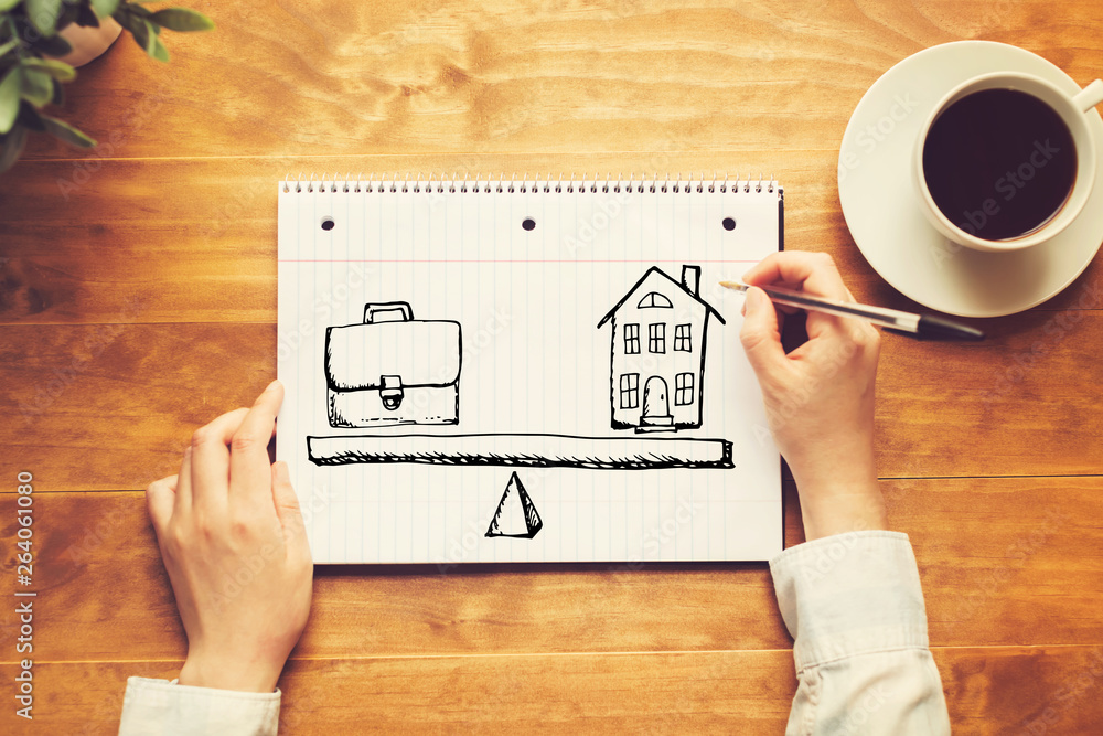 Work and life balance with a person holding a pen on a wooden desk