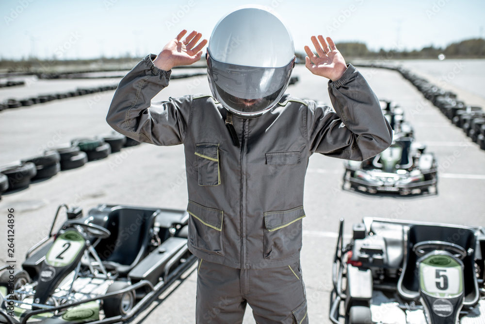 Despair racer in sportswear feeling sad standing as a loser on the go-kart track outdoors