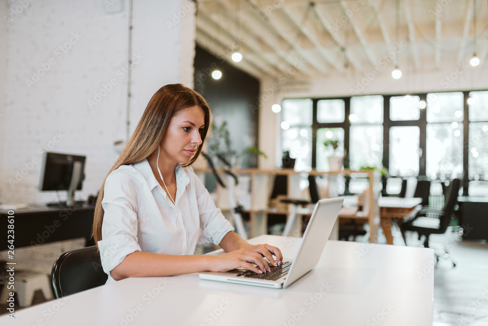 Side view of beautiful young entrepreneur working in modern open space office.