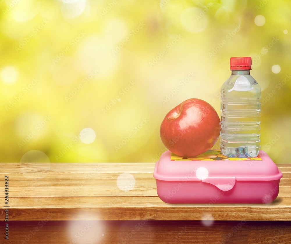 学校桌子上有水和食物的红苹果