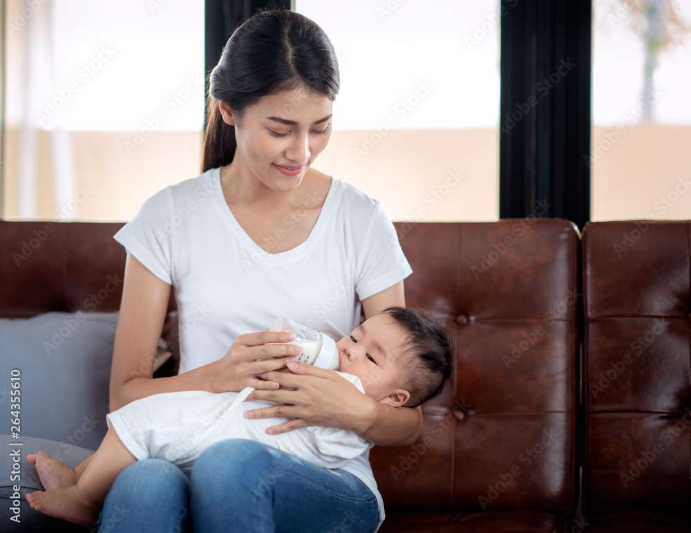 Asian mother feeding milk to her baby by bottle