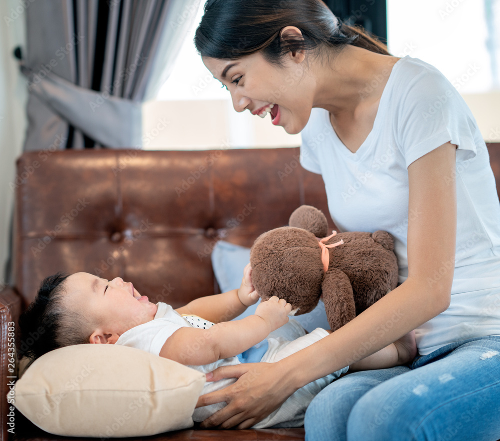 Mother play with her baby by teddy bear