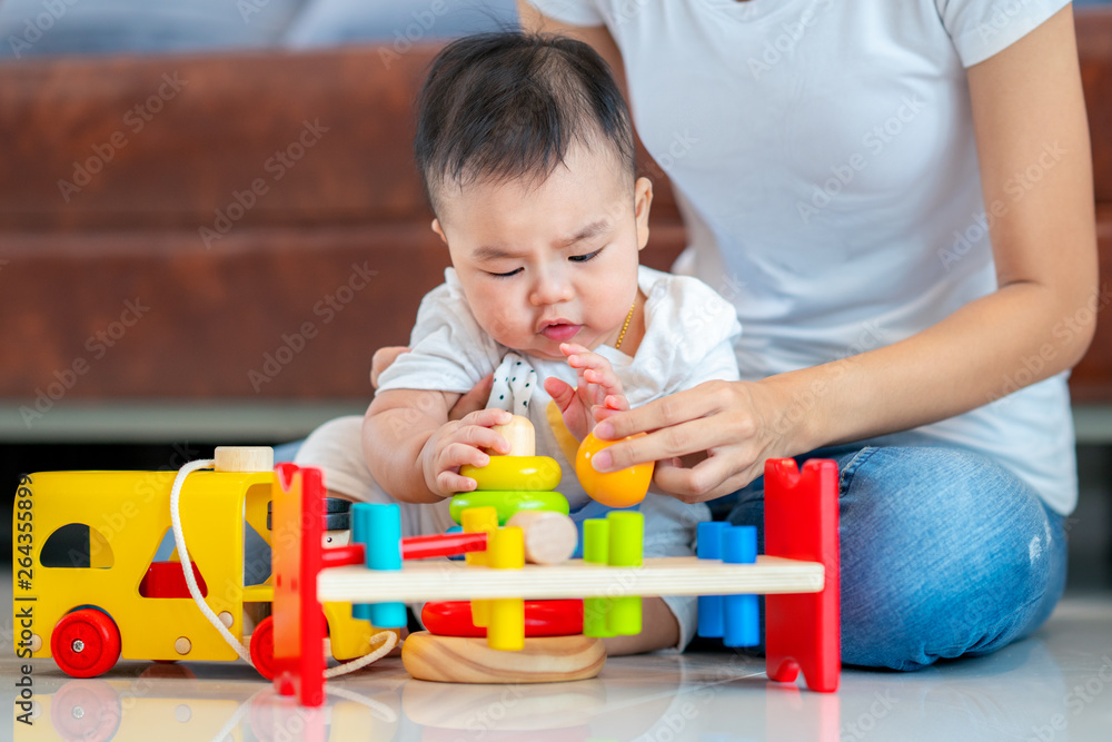 Mother play with her baby by wooded toy