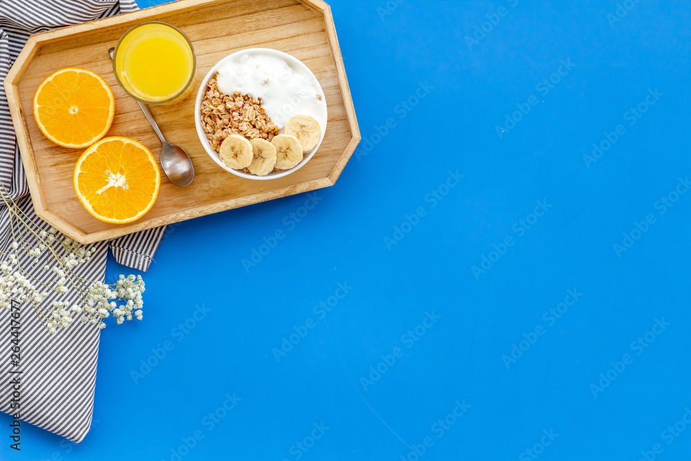 Healthy granola with banana and orange juice for colorful breakfast on blue background top view mock