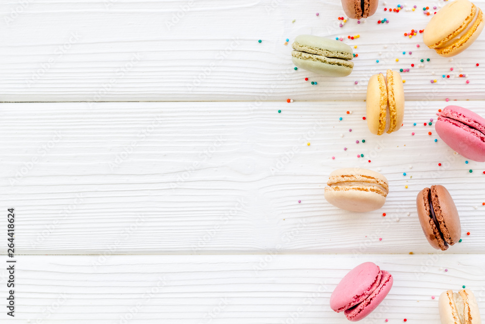 Brignt macarons for sweet break on white wooden background top view mock up