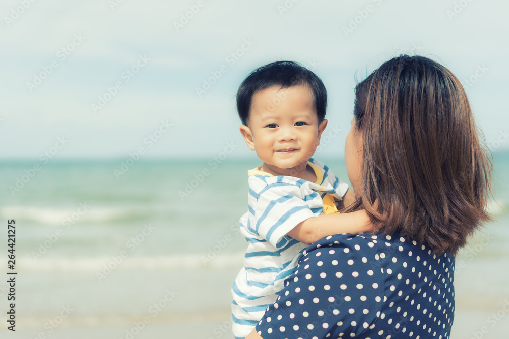 亚洲幸福家庭的母亲和她的孩子在海边户外的肖像。夏天，假期，旅行