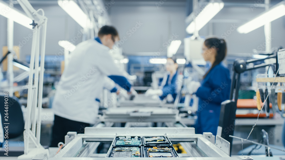 Shot of an Electronics Factory Workers Assembling Circuit Boards by Hand While it Stands on the Asse