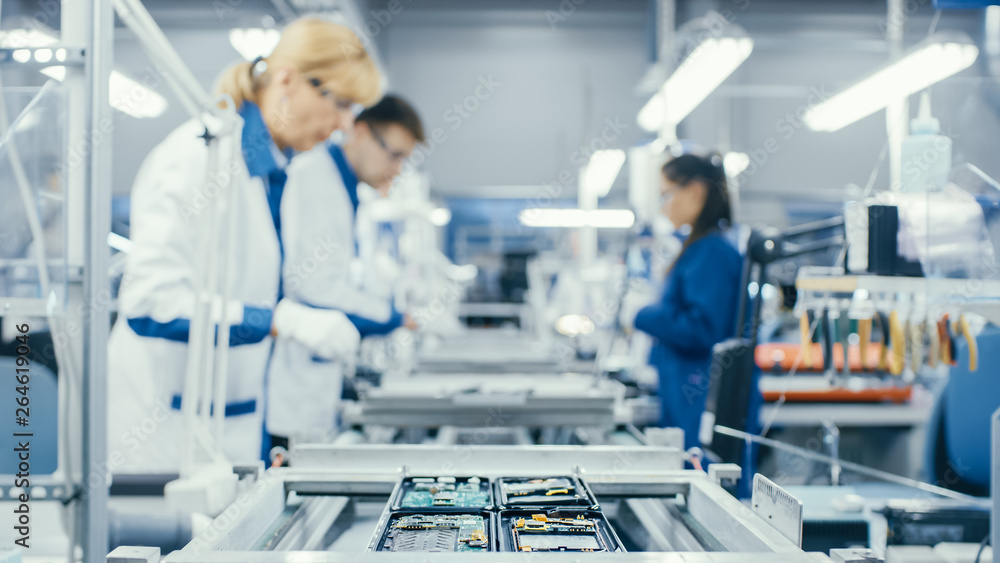 Shot of an Electronics Factory Workers Assembling Circuit Boards by Hand While it Moves on the Assem