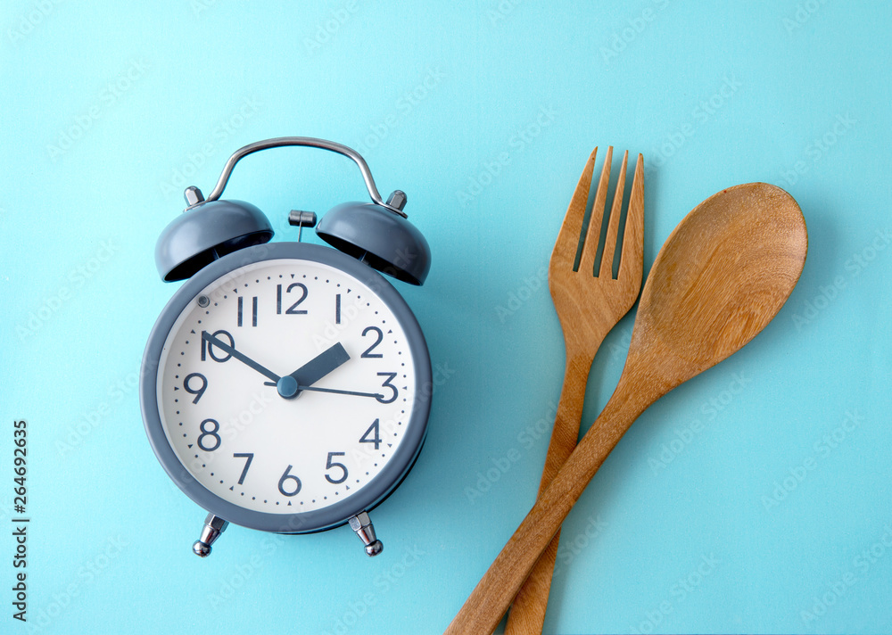 Time to lose weight , eating control or time to diet concept , a alarm clock decoration on blue back