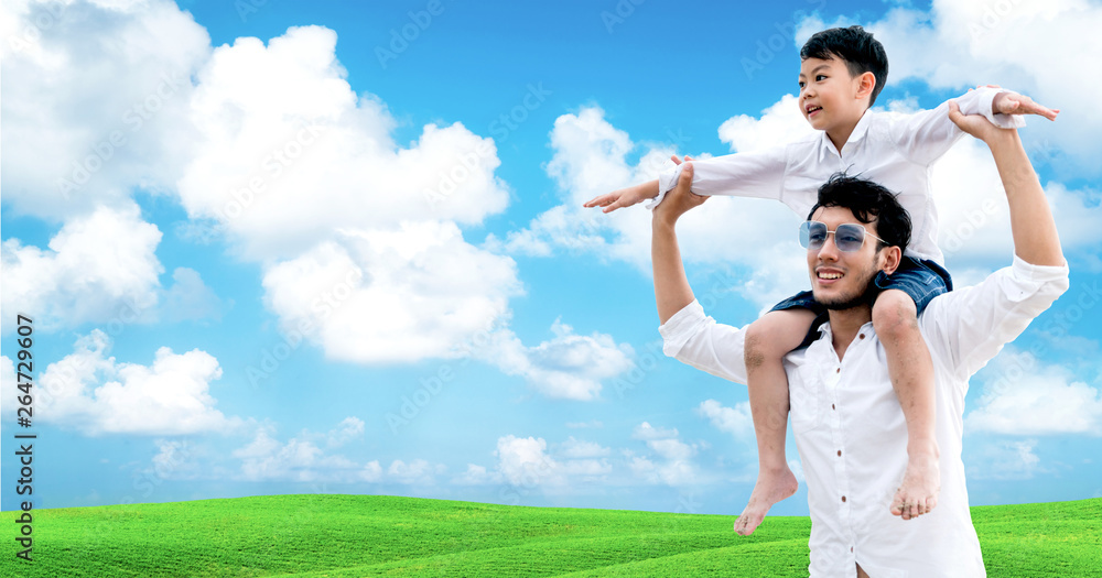 Happy father carrying his son on shoulders is on vacation and escape to nature.