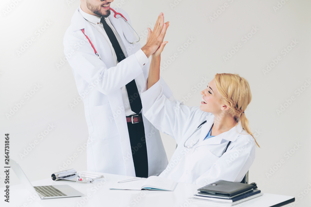 Happy successful doctor celebrates victory in hospital office with another doctor standing beside he