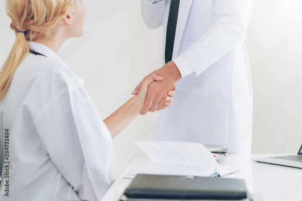 Doctor at the hospital giving handshake to another doctor showing success and teamwork of profession