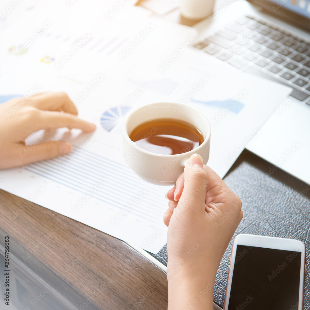 Business concept. Woman reading reports and drinking for rest in office table. Backlighting, sun gla