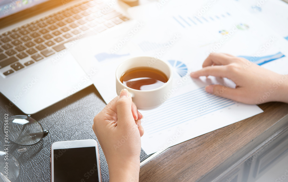 Business concept. Woman reading reports and drinking for rest in office table. Backlighting, sun gla