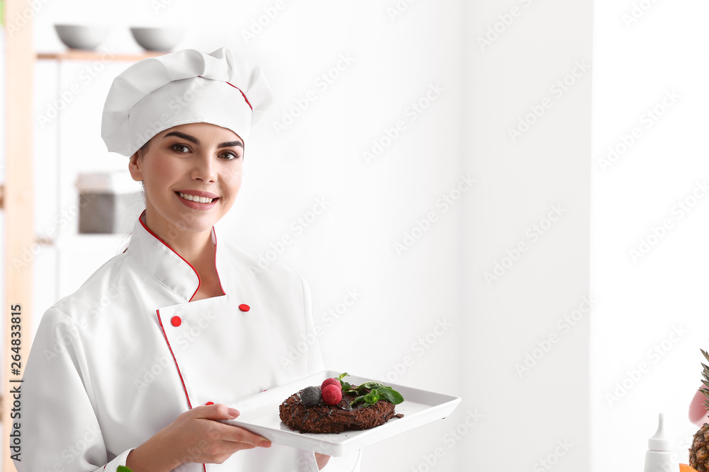 Young female confectioner with tasty dessert in kitchen