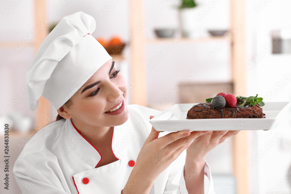 Young female confectioner with tasty dessert in kitchen