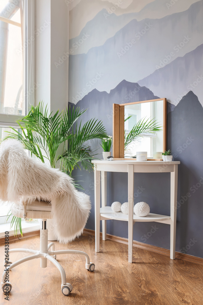 Table with big mirror near grey wall in room