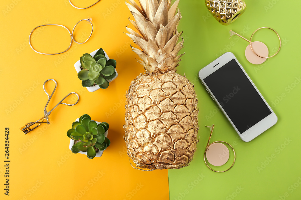 Golden pineapple with mobile phone, plants and female accessories on color background