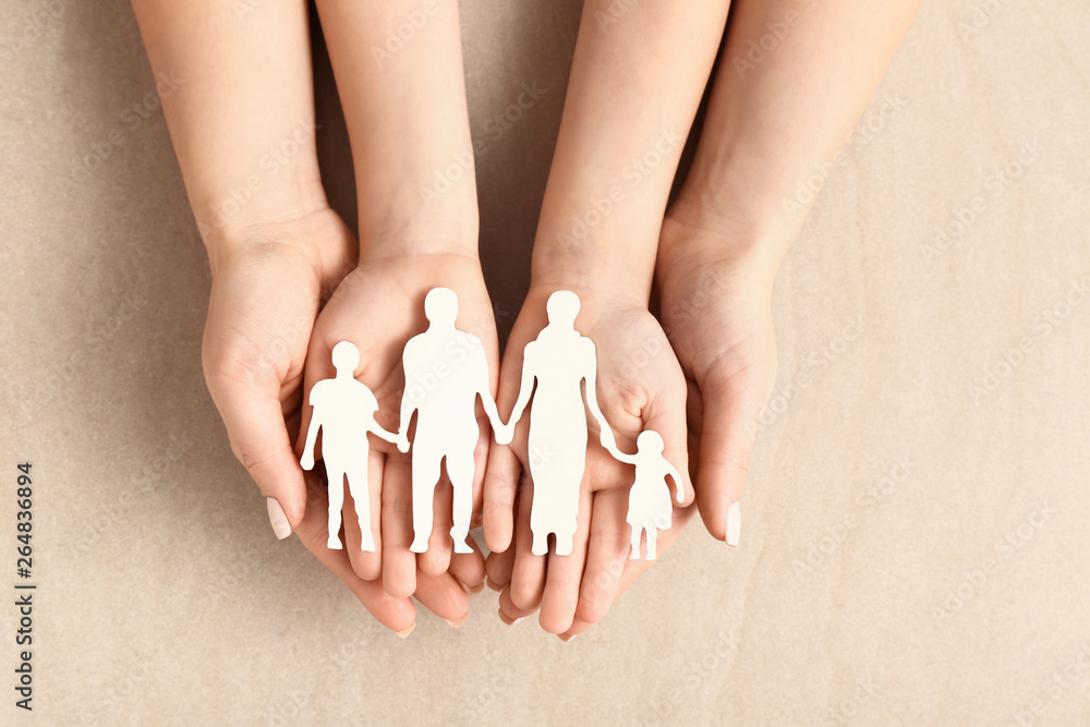 Hands of woman and child with figure of family on light background. Adoption concept