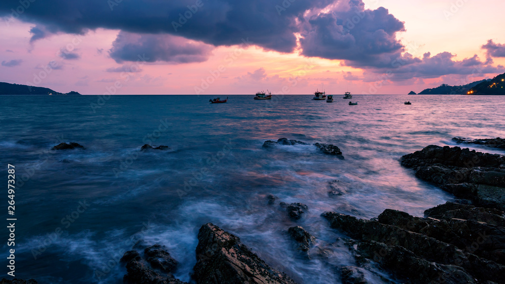 Long exposure image of Dramatic sky and wave seascape with rock in sunset scenery background