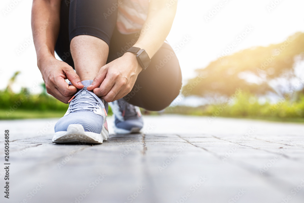 Young woman tying jogging shoes.