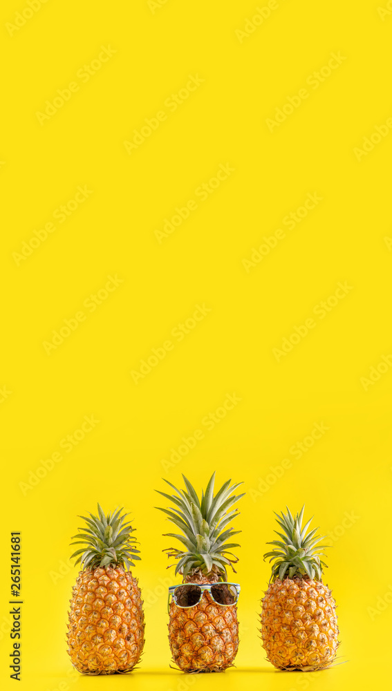 Creative pineapple looking up with sunglasses and shell isolated on yellow background, summer vacati