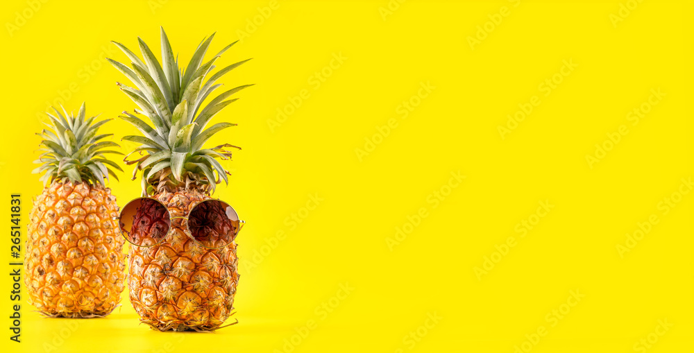 Creative pineapple looking up with sunglasses and shell isolated on yellow background, summer vacati