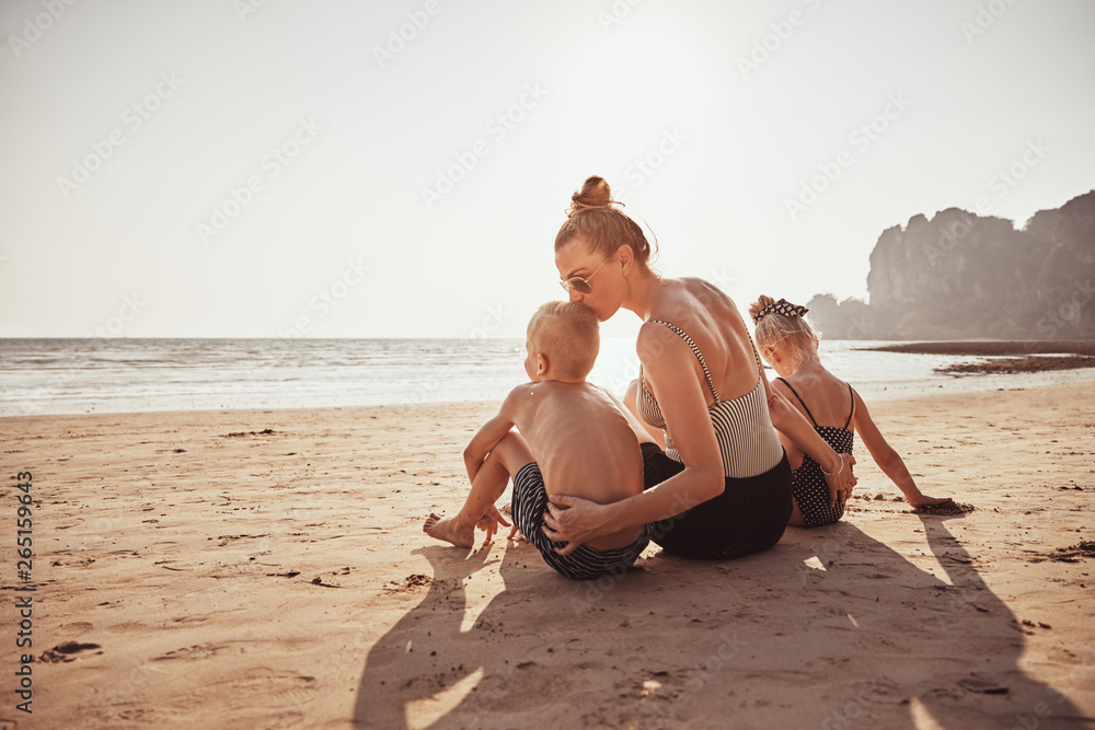 Loving Mother sitting with her children on a sandy beach