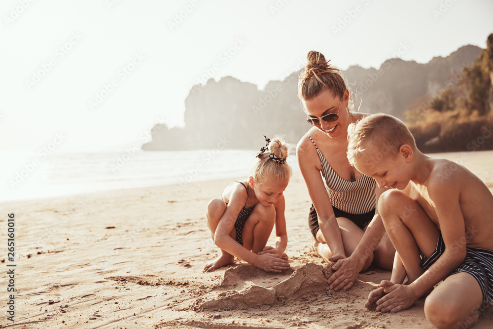 Mother and her cute kids playing on a sandy beach