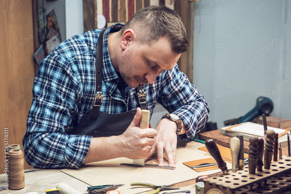 Man working with leather textile at a workshop.