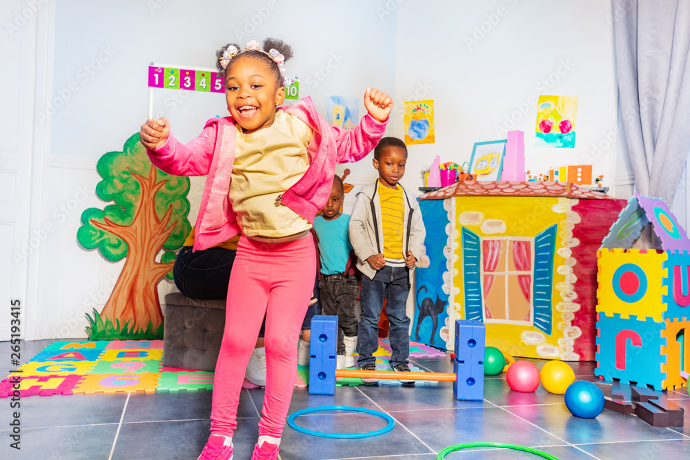 Black little girl jumps over hoops in kindergarten