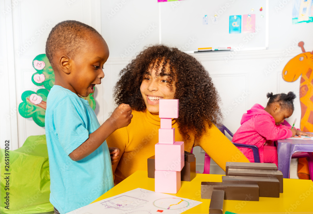 Excited little boy in nursery about block tower