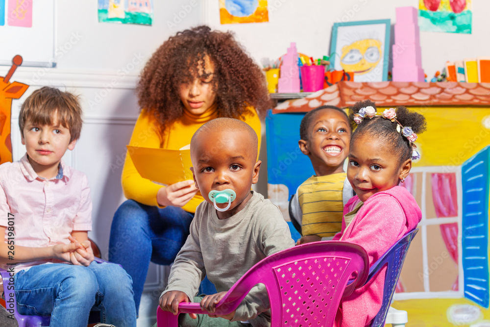 Toddler with pacifier in kids nursery group