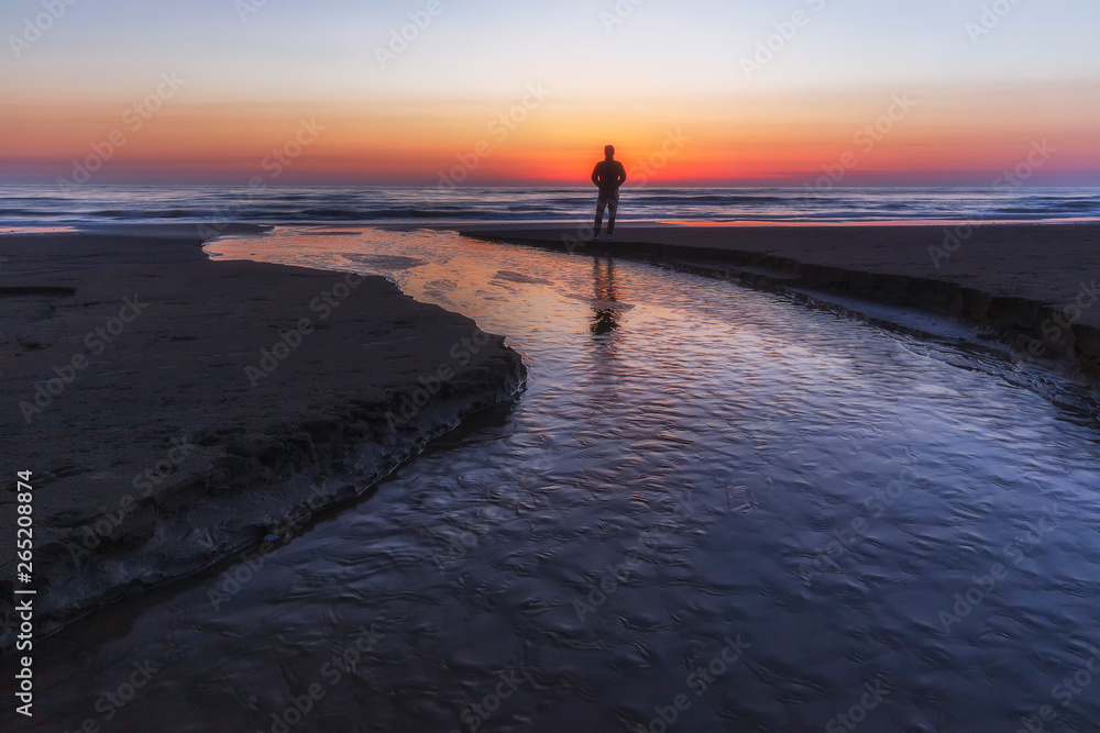 A young guy meets the sunrise by the sea