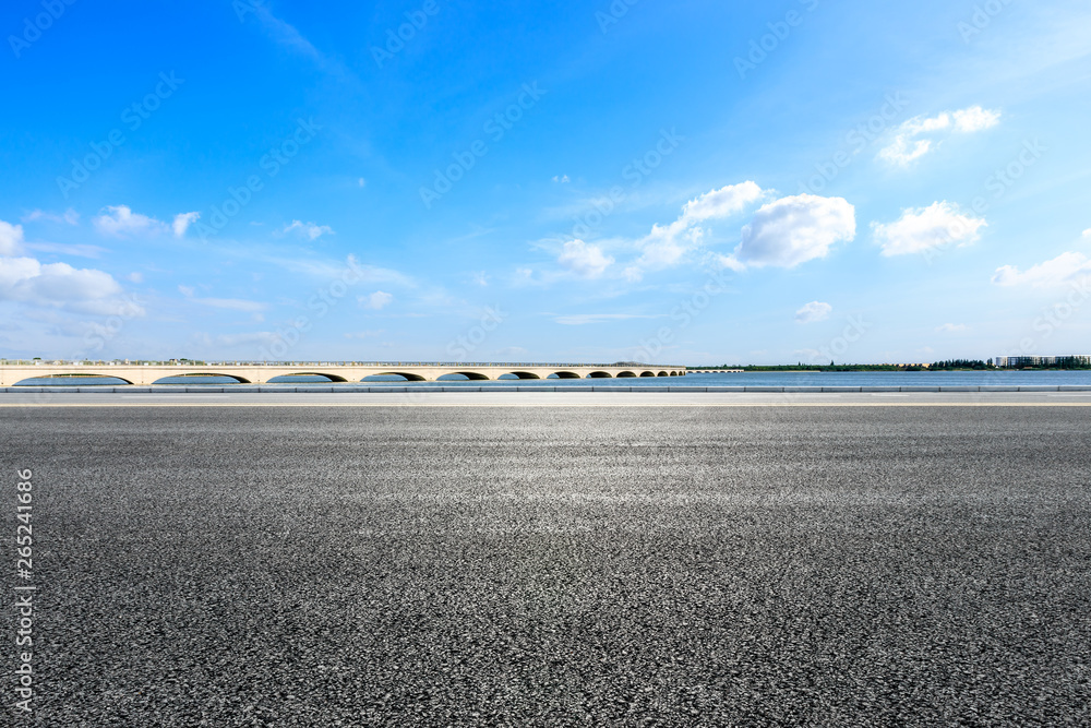 蓝天下有桥的空旷柏油路和湖泊