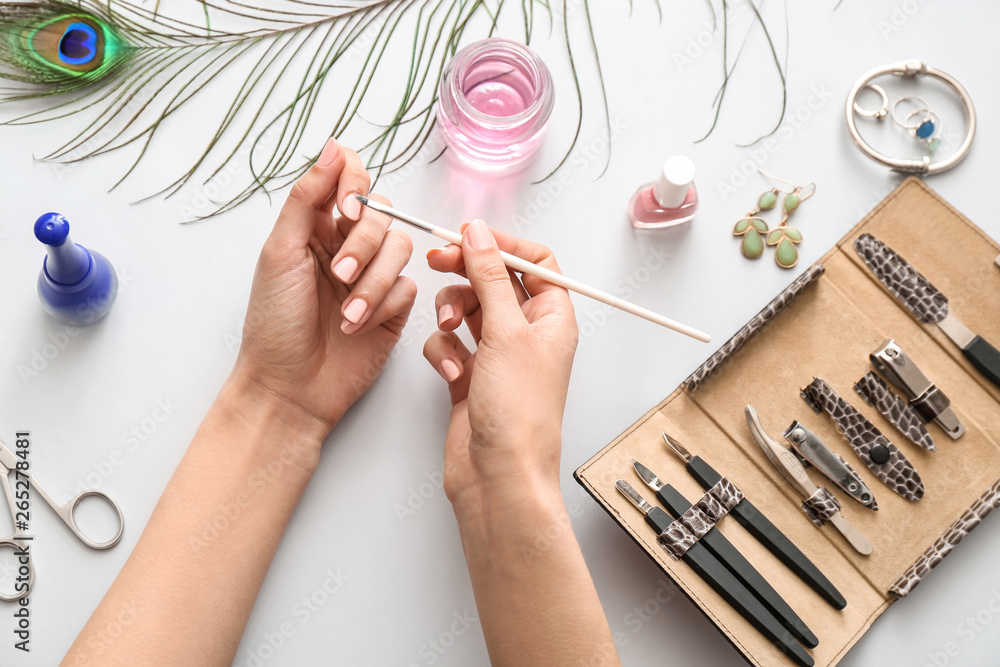 Woman doing manicure on light background