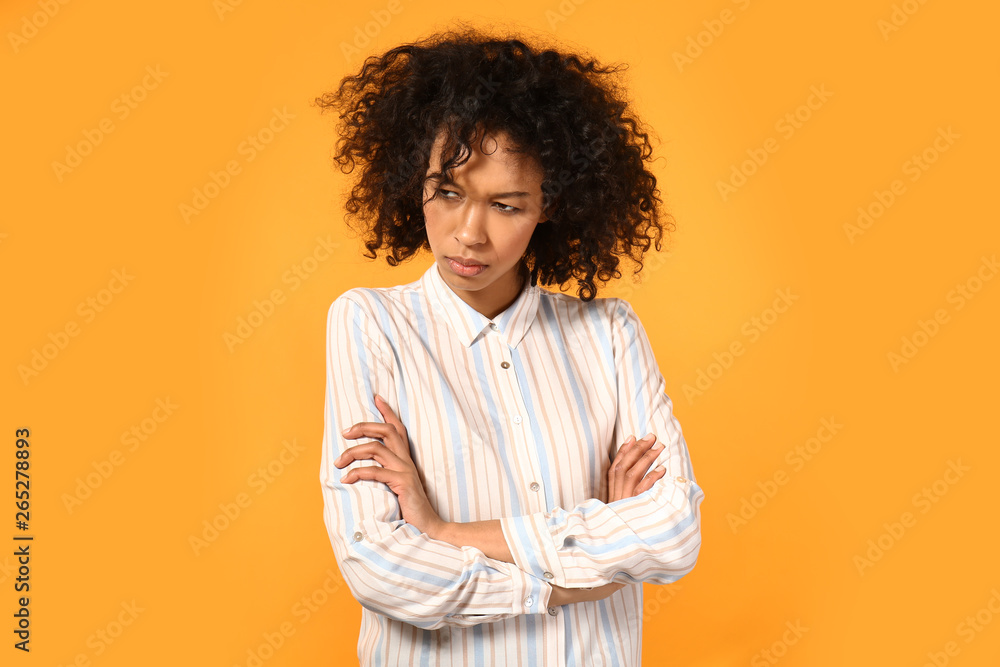 Displeased African-American woman on color background