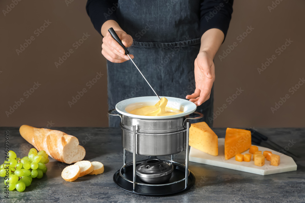 Woman dipping cheese into fondue at table