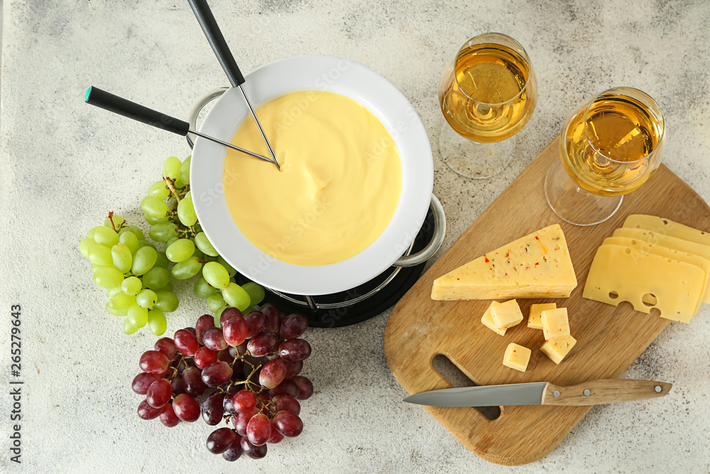 Cheese fondue with glasses of wine on grey background