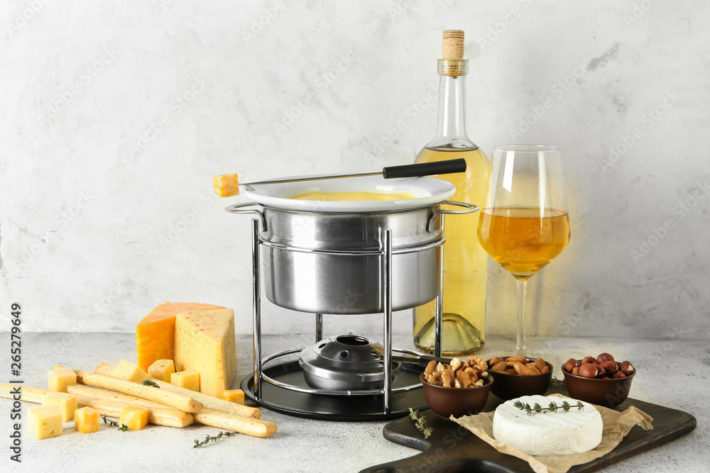 Cheese fondue with snacks and wine on table