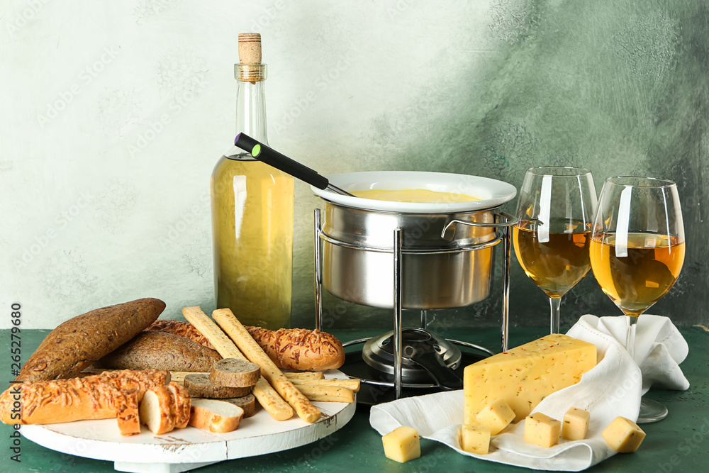 Cheese fondue with snacks and wine on table