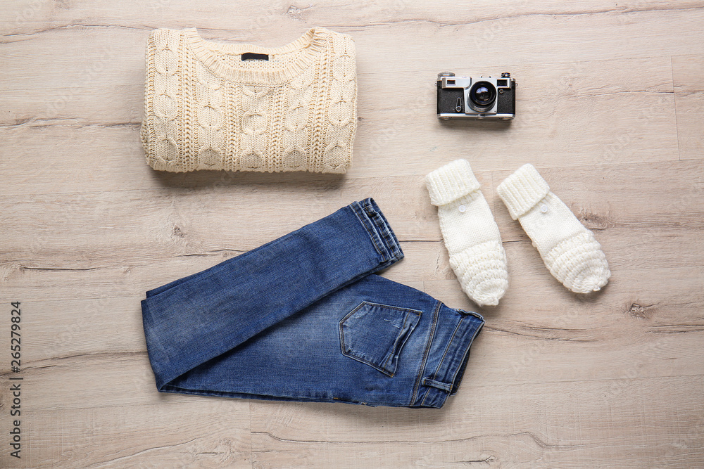 Warm clothes and photo camera on light wooden background