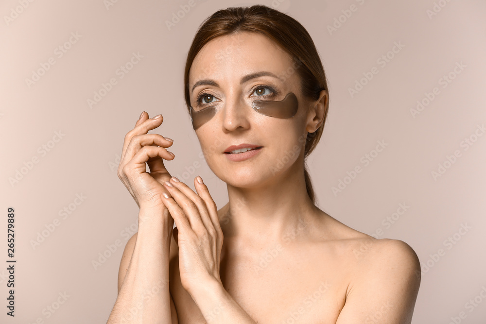 Mature woman with under-eye patches on light background