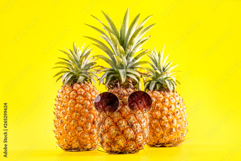 Creative pineapple looking up with sunglasses and shell isolated on yellow background, summer vacati