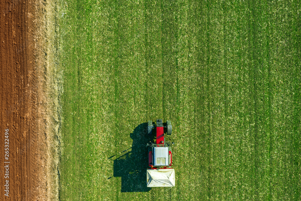 Agricultural tractor fertilizing wheat crop field with NPK