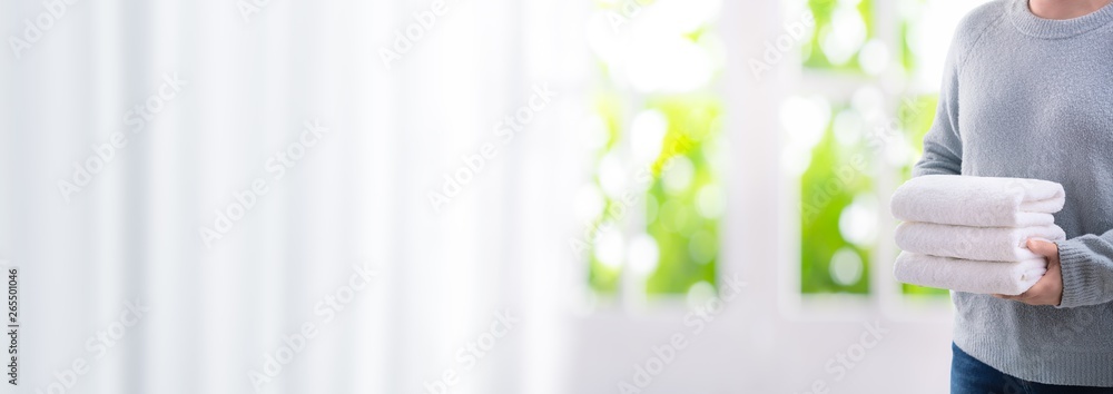 Woman holding stack of fresh white bath clean towels in bedroom interior