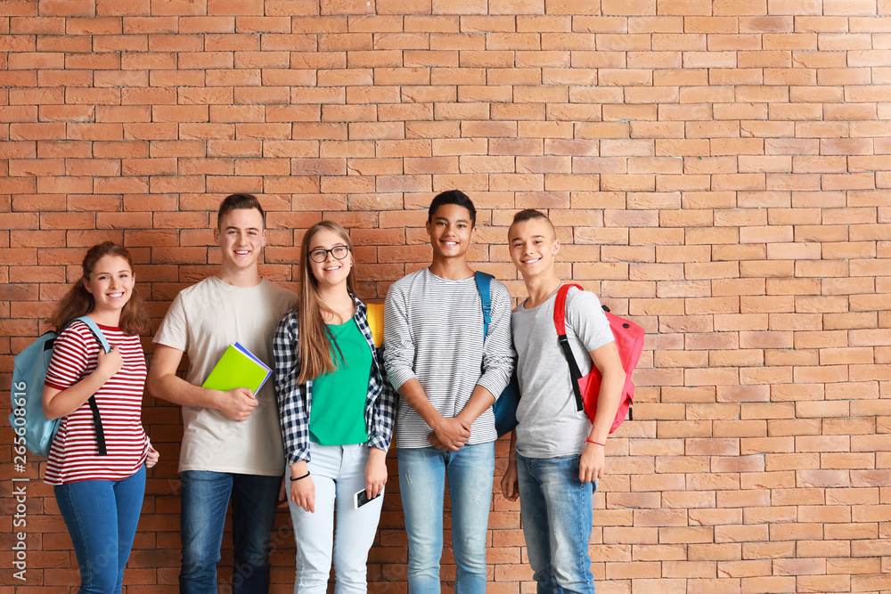 Group of teenagers near brick wall