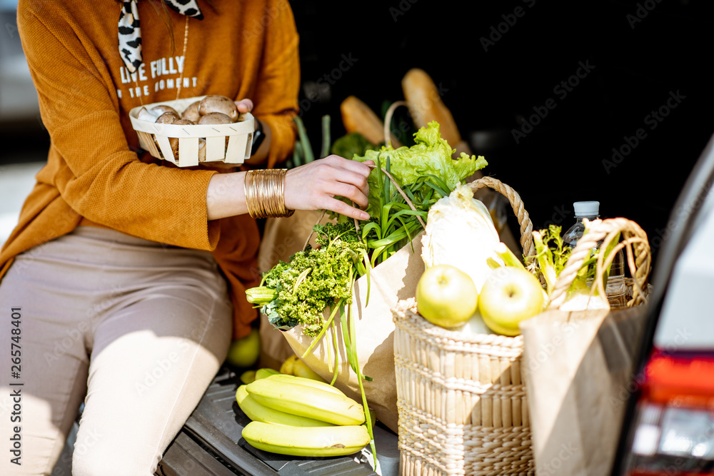 一名妇女将新鲜食品装入汽车行李箱的购物袋